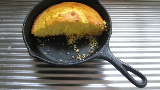 Golden cornbread baked in a black cast iron skillet, with a wedge cut out