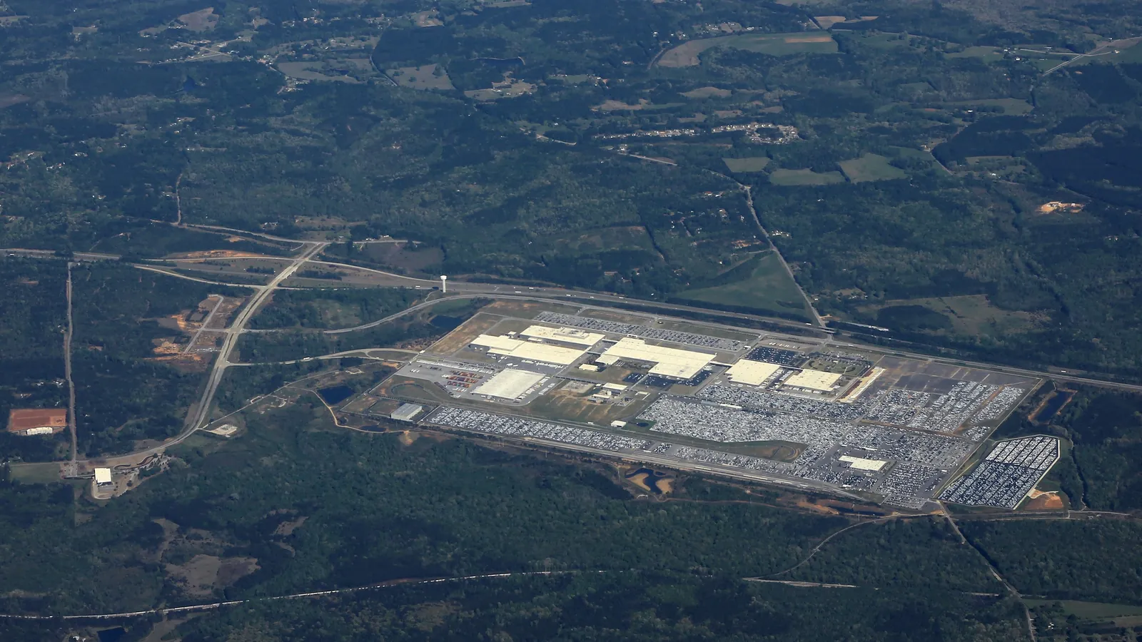 Aerial view of a large car assembly plant and its vehicle lots surrounded by Georgia pine forest