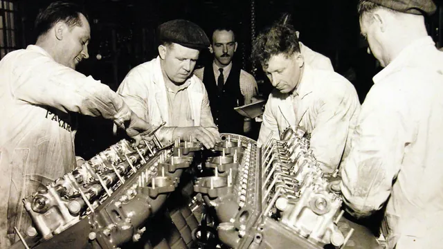 Four machinists in work clothes assemble the supercharger on a large V-12 marine engine at the Packard plant in Detroit in 1941