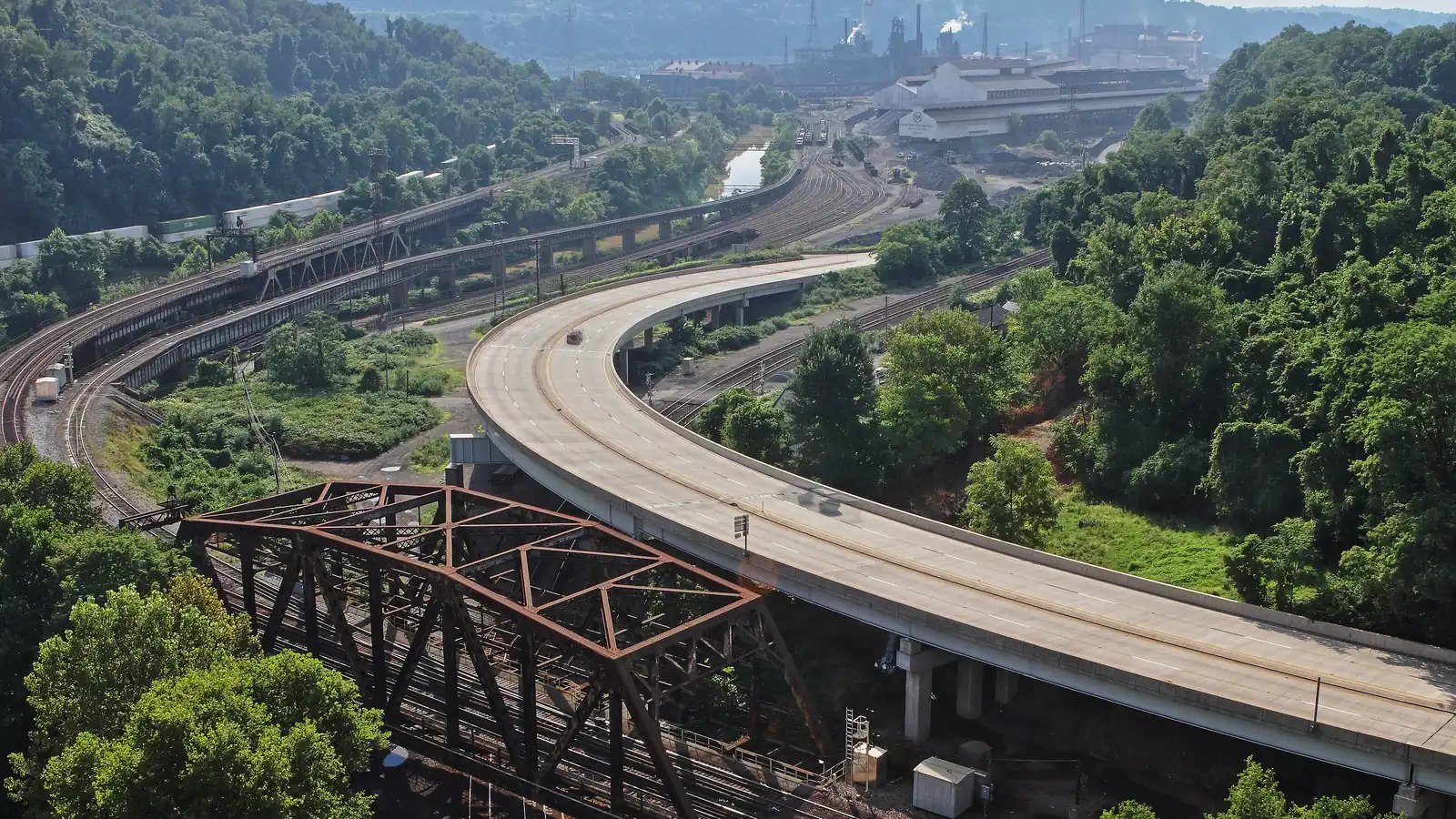 Blast furnace and mill buildings of the Edgar Thomson Steel Works beside a road and a creek in Braddock, Pennsylvania