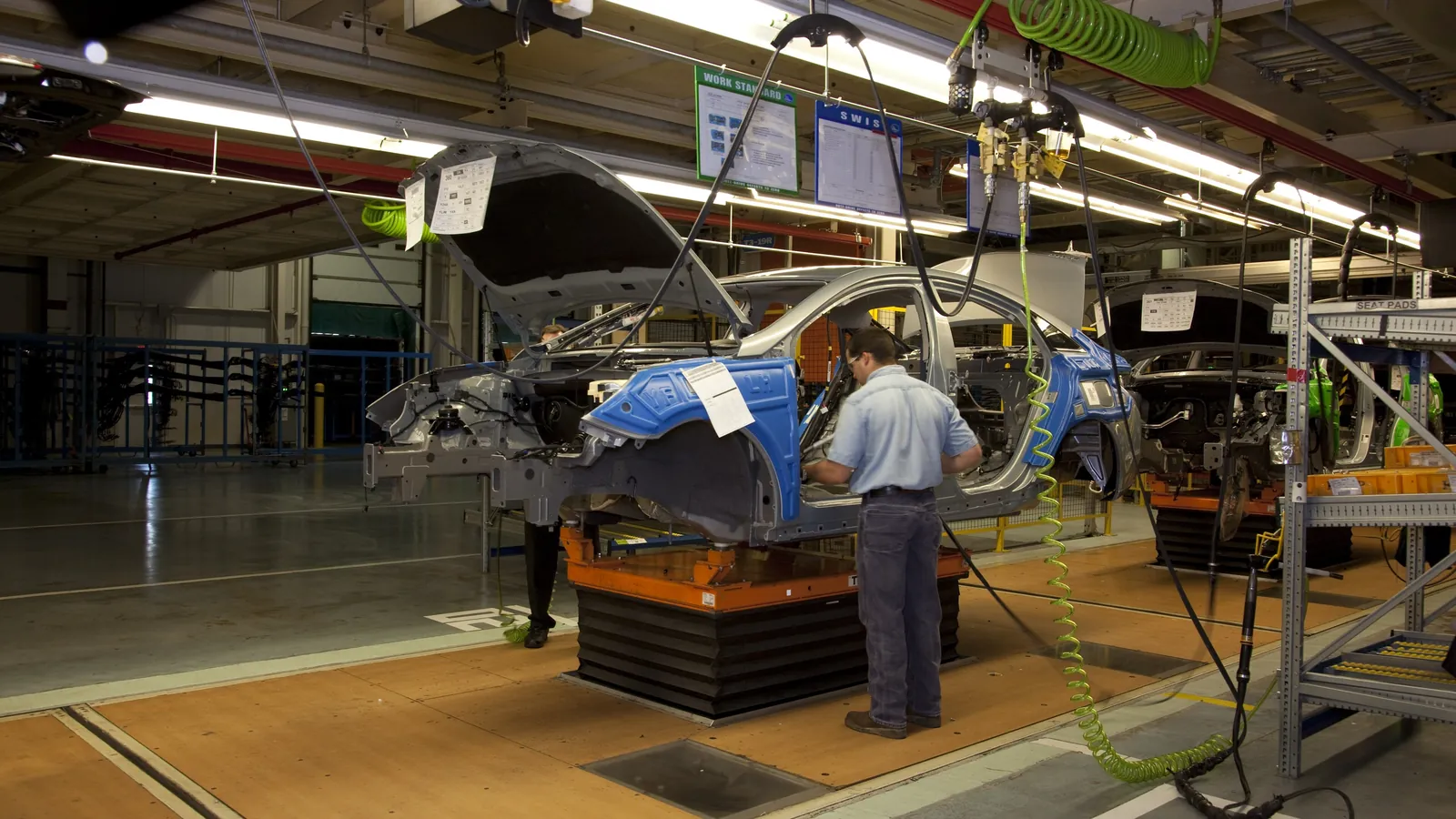 A worker in a blue shirt checks a car body on a moving assembly line inside the Hyundai plant near Montgomery, Alabama