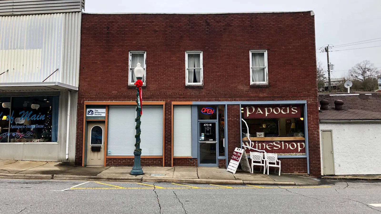 A two-story red brick storefront building with a small wine shop and other local businesses on a quiet small-town street