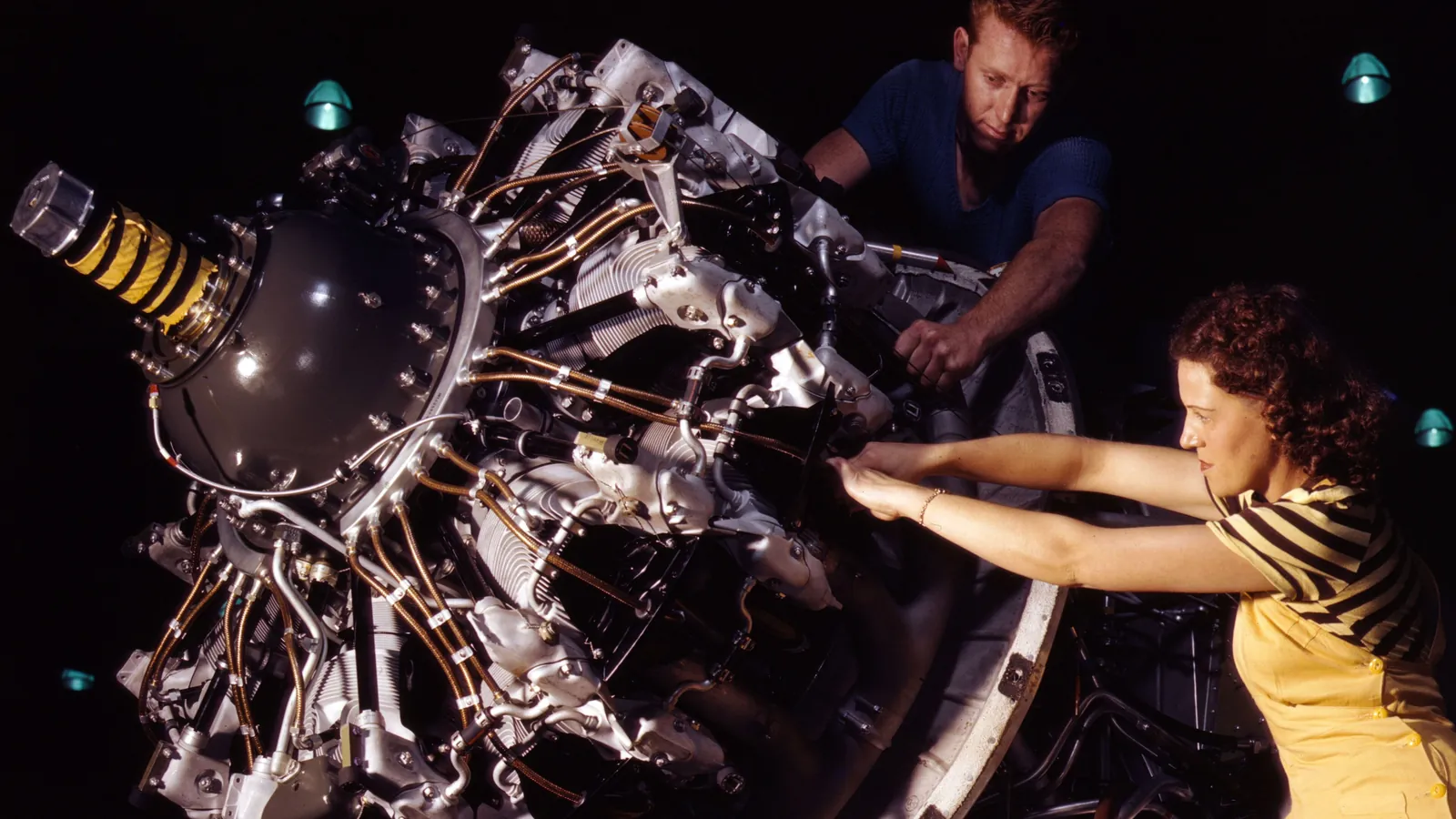 A woman in a striped shirt works on a Pratt & Whitney radial engine for a C-47 transport at the Douglas Aircraft plant in Long Beach, California, in 1942